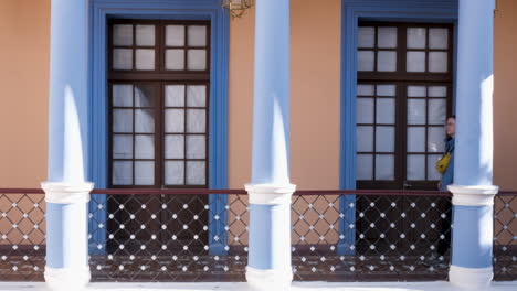 traveler walks by blue colonial pillars at museo charcas in sucre, bolivia, exploring stunning architecture