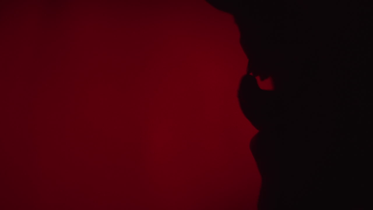 Silhouette of a person against a dark red background