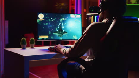 man at home playing singleplayer videogame with spaceship shooting laser beams at asteroids