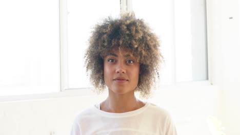 biracial young woman with curly hair standing, looking forward