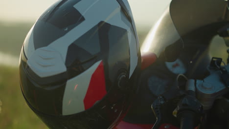 close-up of a motorcycle handlebar with a helmet resting on it and the ignition key inserted, with natural light reflecting softly