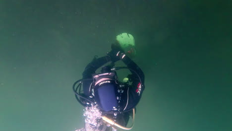 disparo submarino cinematográfico en cámara lenta de un buzo en un lago verde y brumoso