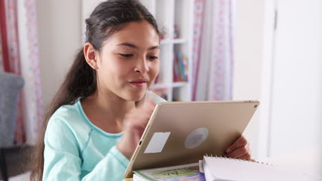 Una-Joven-Sentada-Frente-A-Un-Escritorio-En-El-Dormitorio-Jugando-Con-Una-Tableta-Digital