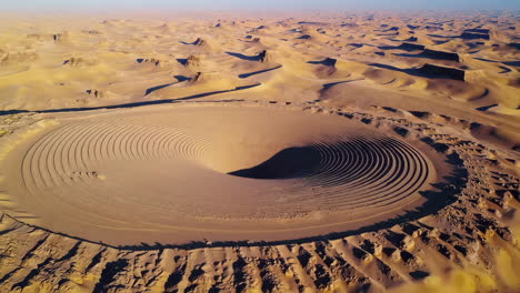 aerial view of a unique circular sand formation in a vast desert landscape