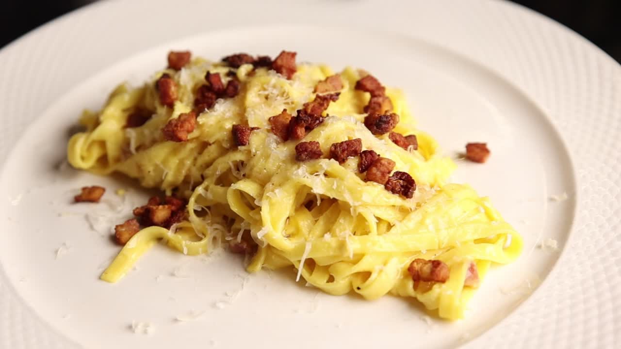 Deliziosa pasta alla Carbonara servita con pancetta e formaggio grattugiato