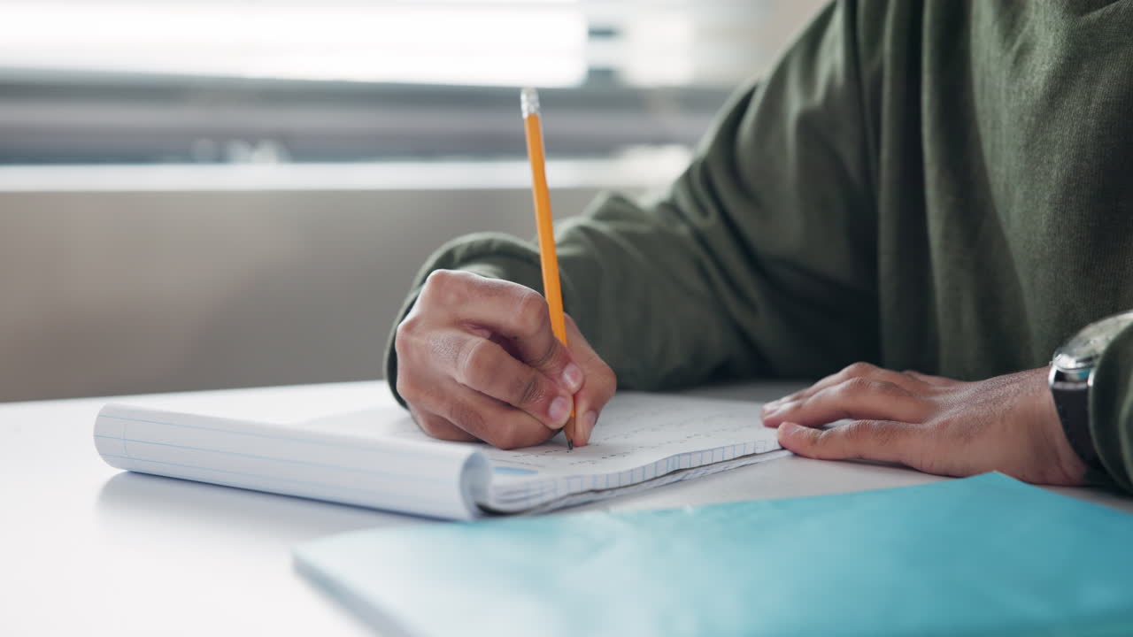Person writing in a notebook with a pencil