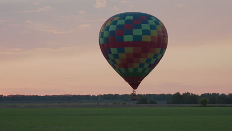 couple enjoying sunset hot air balloon ride over agriculture with burner flame rising low above ground against pastel sky creating serene aerial adventure