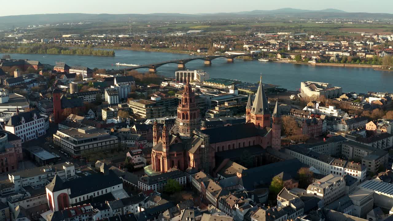 Riprese aeree con drone che si allontanano dalla cattedrale di Magonza in una calda giornata di primavera, mostrando il fiume blu sullo sfondo.