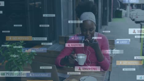 Animación-De-Notificaciones-De-Redes-Sociales-Sobre-Una-Mujer-Afroamericana-Usando-Un-Teléfono-Inteligente-En-Un-Café-Callejero