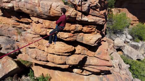 male highliner sitting on a rope over rocky mountains 4k