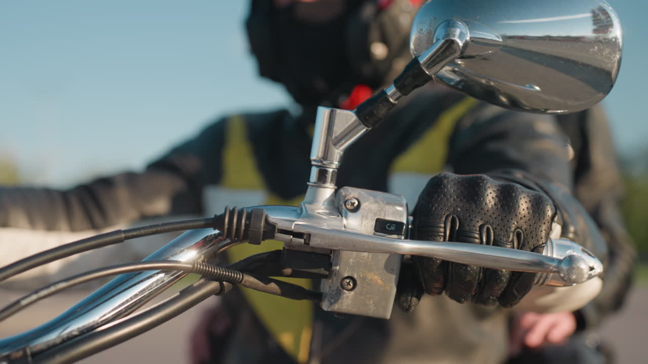 Close up of motorbike rider in black helmet and leather jacket, eyes focused ahead, with blurred passenger visible in background, capturing strong sense of travel