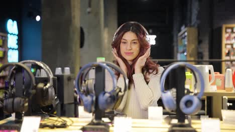 woman trying on headphones in electronics store. high quality fullhd footage