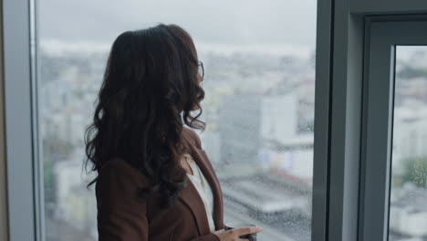 Portrait-businesswoman-drinking-coffee-at-office-window.-Woman-holding-cup.