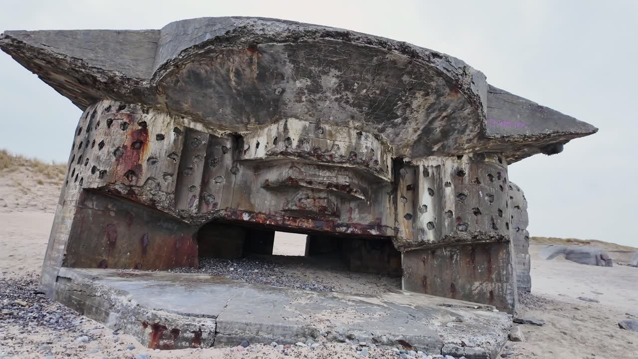 A ruined WW2 bunker with a huge opening for a cannon stands on the beach. Denmark Scandinavia.