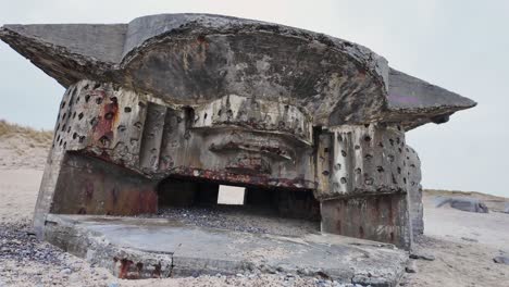 a ruined ww2 bunker with a huge opening for a cannon stands on the beach. denmark scandinavia.