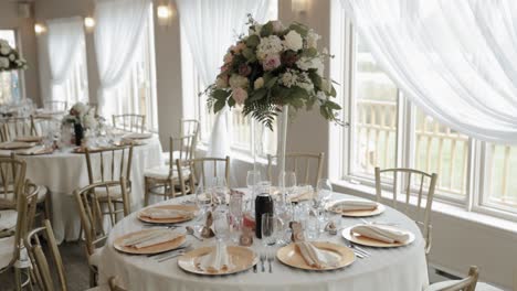 Elegant-reception-hall-in-the-middle-of-Quebec,-with-beautiful-tall-vase',-pink-and-white-roses-and-gold-plates