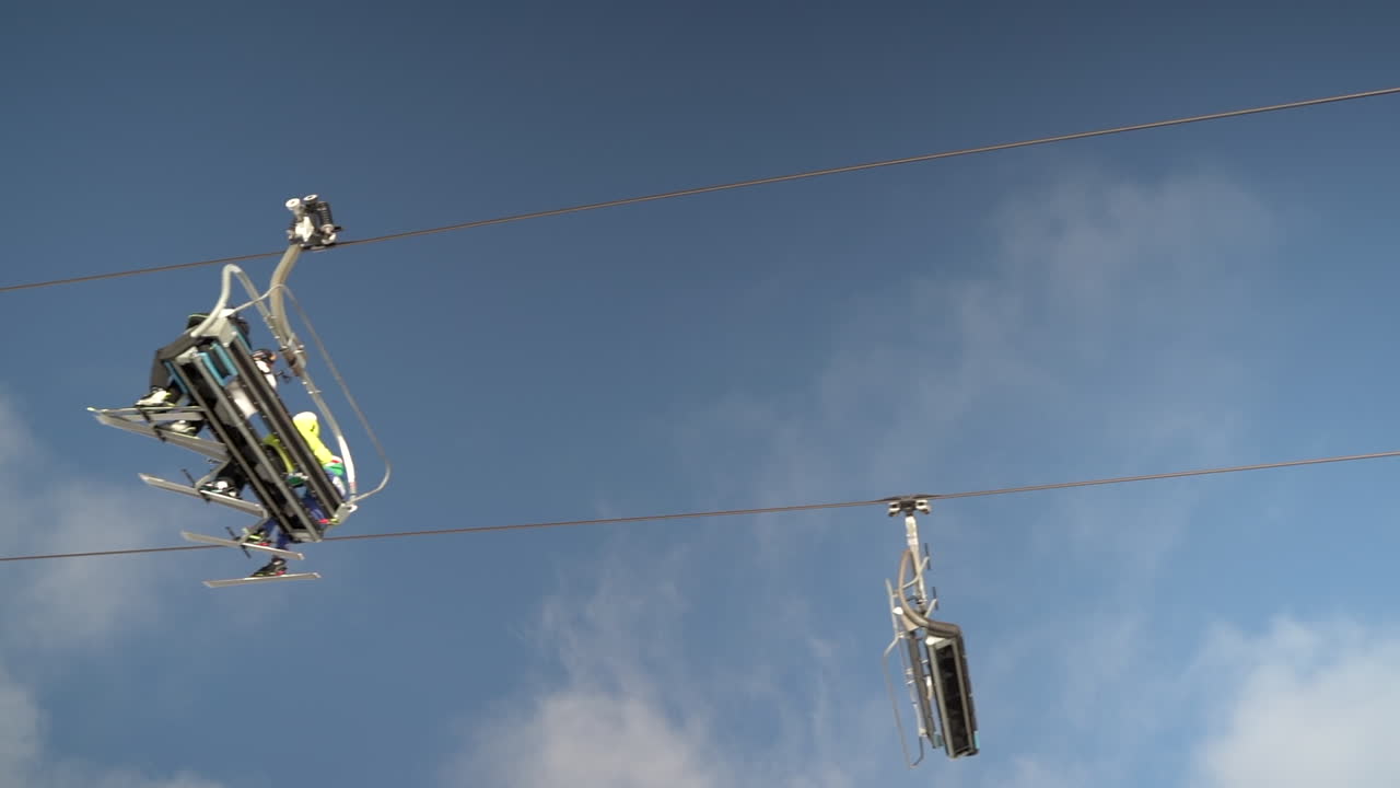 lado debajo de la vista de las unidades de telesillas de esquí que cruzan el marco con el cielo azul y las nubes esponjosas