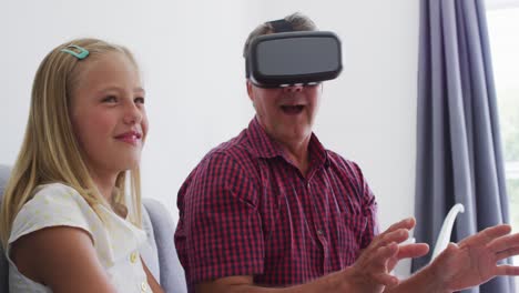 nieta caucásica ayudando a su abuelo a usar auriculares vr en casa