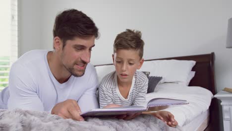 Vater-Und-Sohn-Lesen-Ein-Geschichtenbuch-Im-Schlafzimmer-Zu-Hause-4k