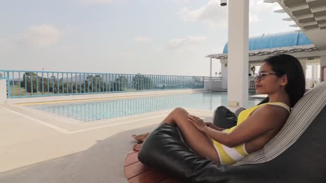 relaxed tourist sitting near a pool enjoying her summer vacations in a tropical destination