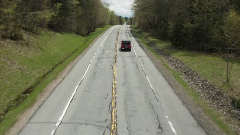drone shot, following a red car, while panning the camera up.