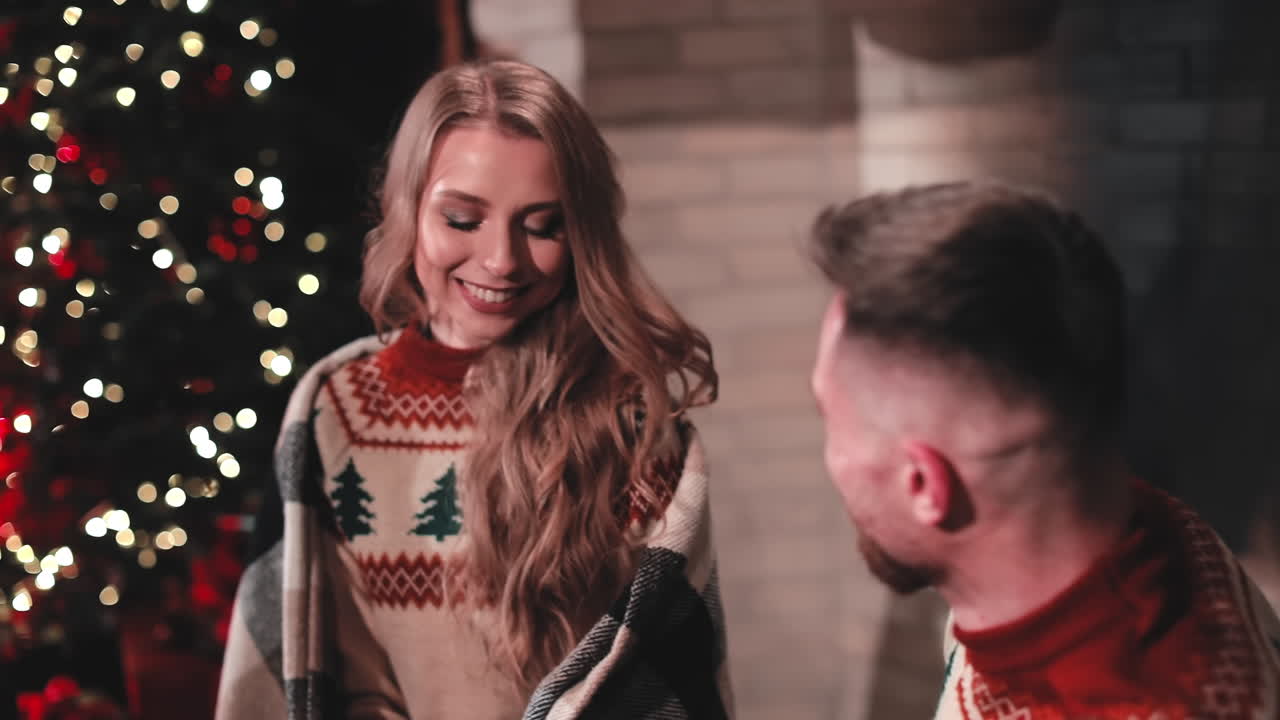 Beautiful couple in love near fireplace. Loving man and woman inside bonding and hugging in cold evening. Couple in love kissing each other