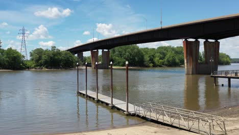 Aerial-view-of-taking-off-from-a-sandy-beach-showing-off-a-bridge-spanning-the-river