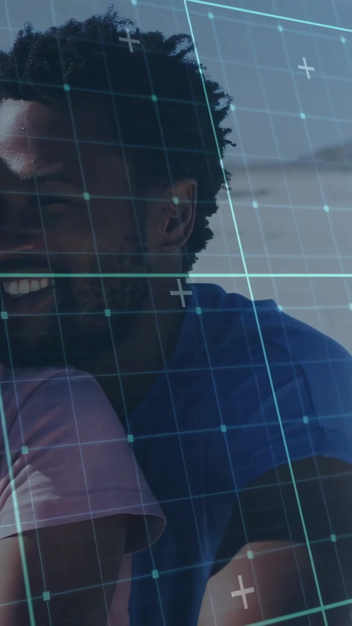 Vertical video: Leaning right man in blue tee hugging her in pink, smiling by shore under teal grid