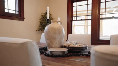 clay-vase,-candles,-and-plates-on-a-wooden-dining-table-within-the-dining-room-of-a-home