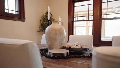 clay vase, candles, and plates on a wooden dining table within the dining room of a home