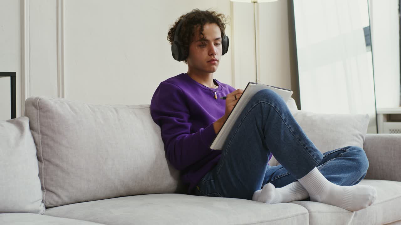 joven dibujando mientras escucha música en casa