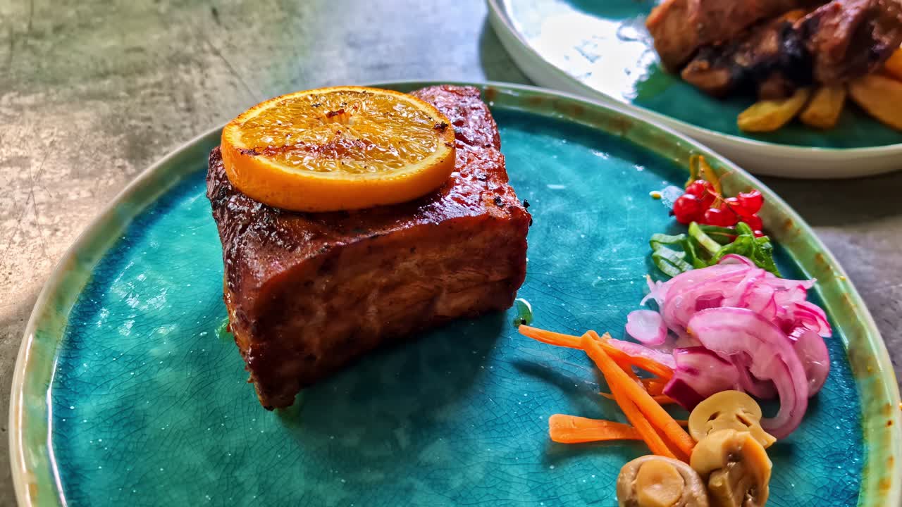 Salmon fillet grilled with orange slice on wooden plate, charred edge and rustic style