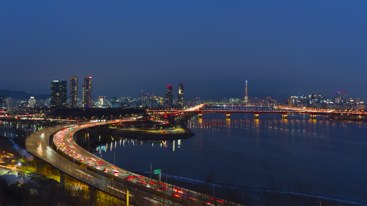 Vista aerea time-lapse dell'ora blu dello skyline di Seul con la Lotte World Tower, ponti illuminati sul fiume Han, tra cui il ponte Seongsu, l'autostrada Gangbyeonbuk-ro con scie luminose di traffico intenso