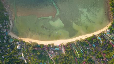 un dron aéreo de 4k empuja la toma de la playa de ensalada en koh phangan en tailandia con barcos de pesca, agua verde azulado, coral y selvas verdes
