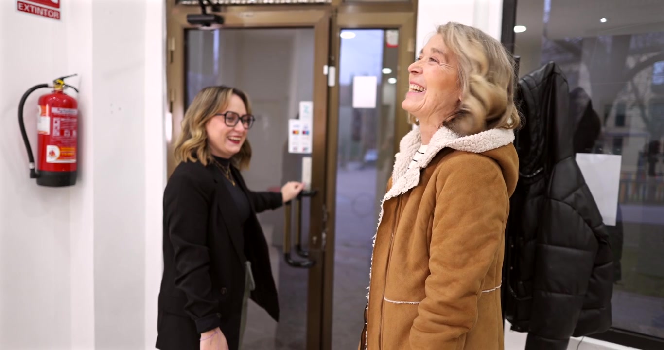 Twee vrouwen praten en lachen in een kantoorentree