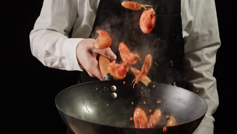 chef cooking shrimp in a wok