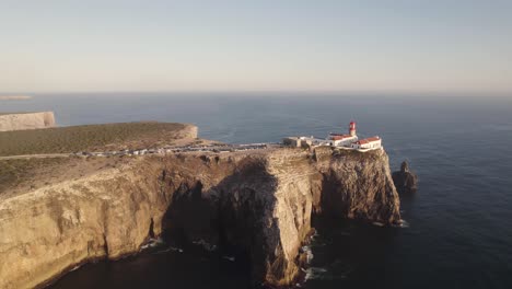 cinematic aerial shot of cape saint vincent lighthouse on eroded high cliff surrounded by atlantic ocean