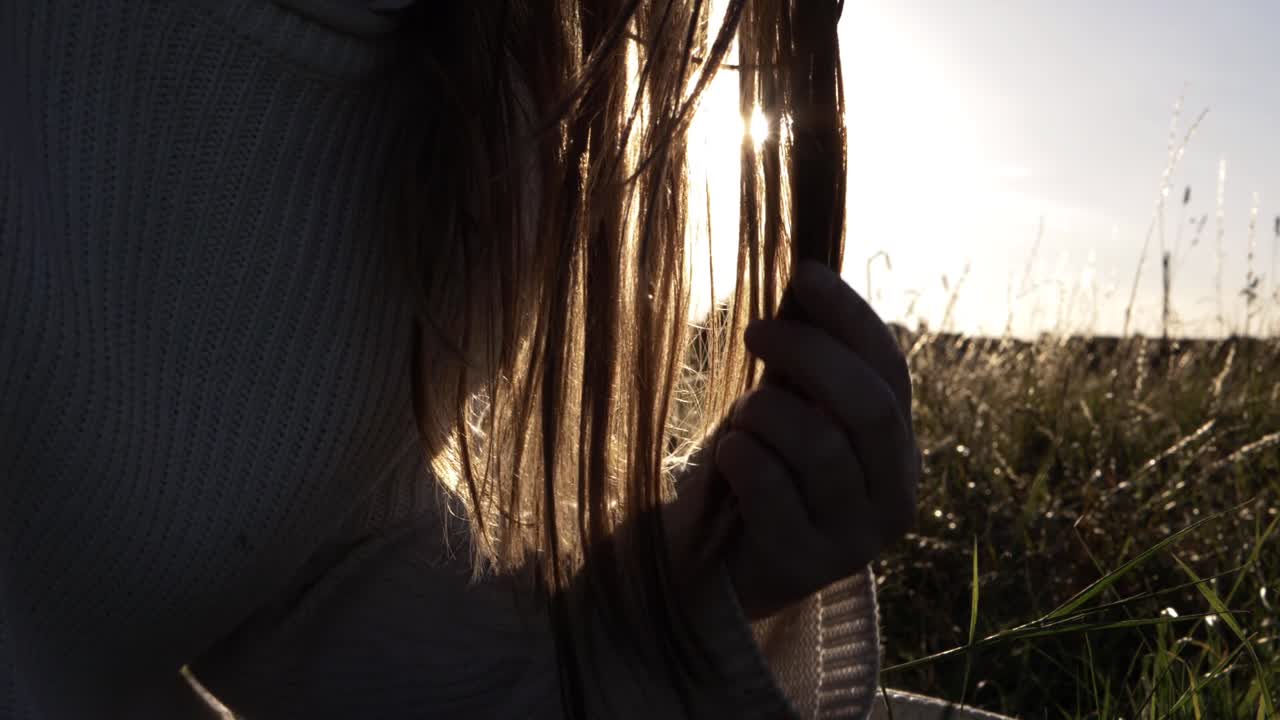 Woman playing with her long hair silhouette against sunshine background close up shot
