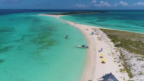 Vista-Aérea-Lancha-Estacionada-En-La-Isla-De-La-Costa-Tropical-De-Arena-Blanca,-La-Gente-Viaja-Destino-Cayo-De-Agua