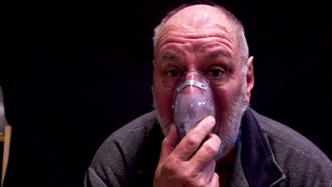 A-mature-aged-balding-man-breathing-with-an-oxygen-mask