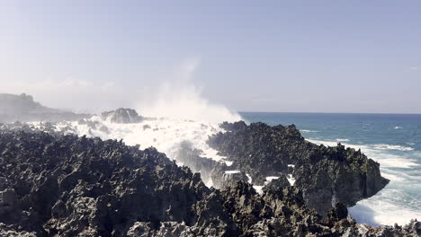 large waves crash against a volcanic rock formation along the coast of indonesia