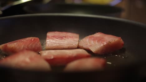 chef placing fish steaks on a hot and sizzling fry pan