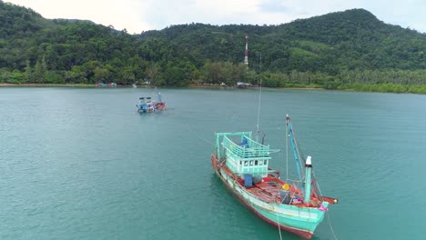 drone shot of a sinking fishing boat being towed by another boat