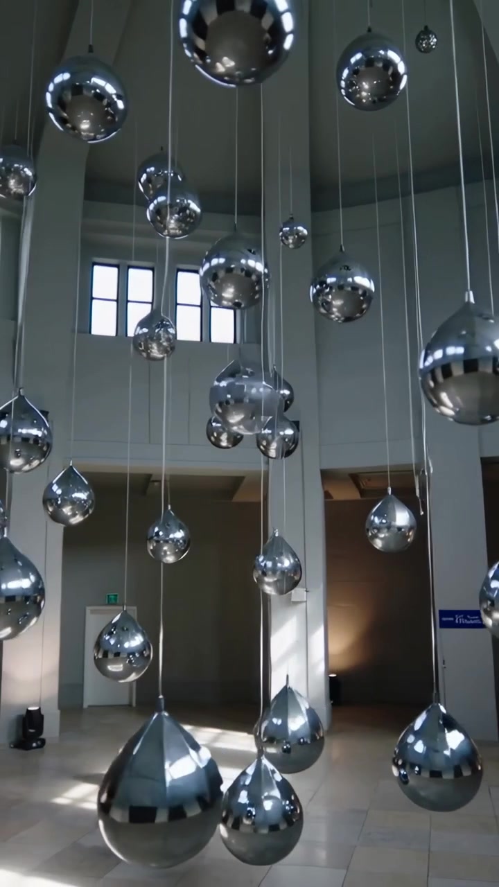 Vertikal video: Viser skinnende metaldråber, der svajer i en rotunde, mens kameraet trækker sig tilbage for at afsløre