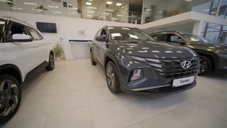 young car salesman showing to young couple new automobile at dealership salon.