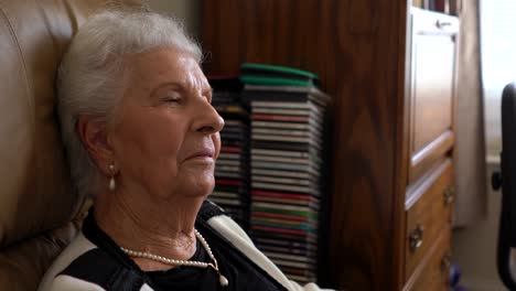 Closeup-of-elderly-woman-sitting-in-a-comfortable-chair-with-her-head-back-talking-gently