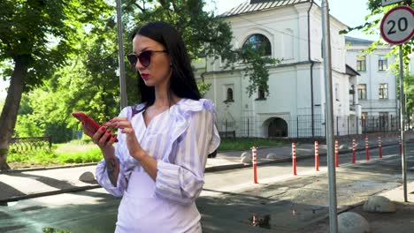 stylish woman dial number on phone and start talking standing at urban street