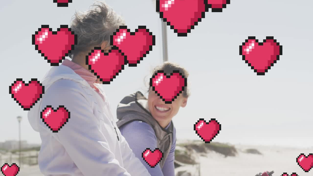 해변에서 이야기하는 행복한 여성 위에 떠다니는 빨간 픽셀 심장의 애니메이션