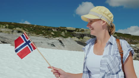 woman with the flag of norway on a snowy peak summer the snow has not melted yet tourism and travel