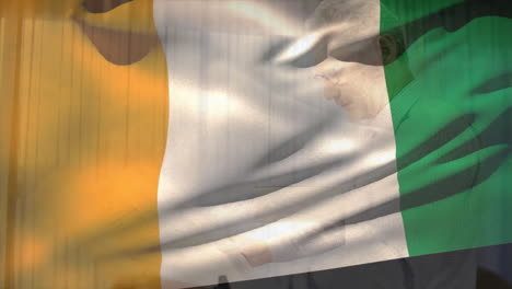 animation of flag of ivory coast over smiling caucasian male architect holding blueprints